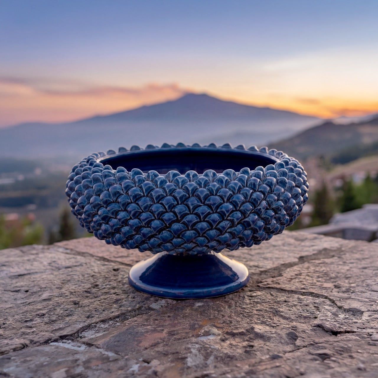 Centrotavola blu ceramiche Caltagirone fatti a mano su pietra, sfondo montagna al tramonto